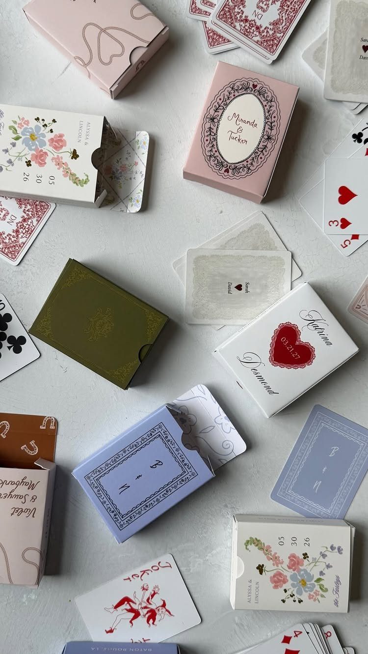 Custom playing card decks in various colors and designs scattered on white background.
