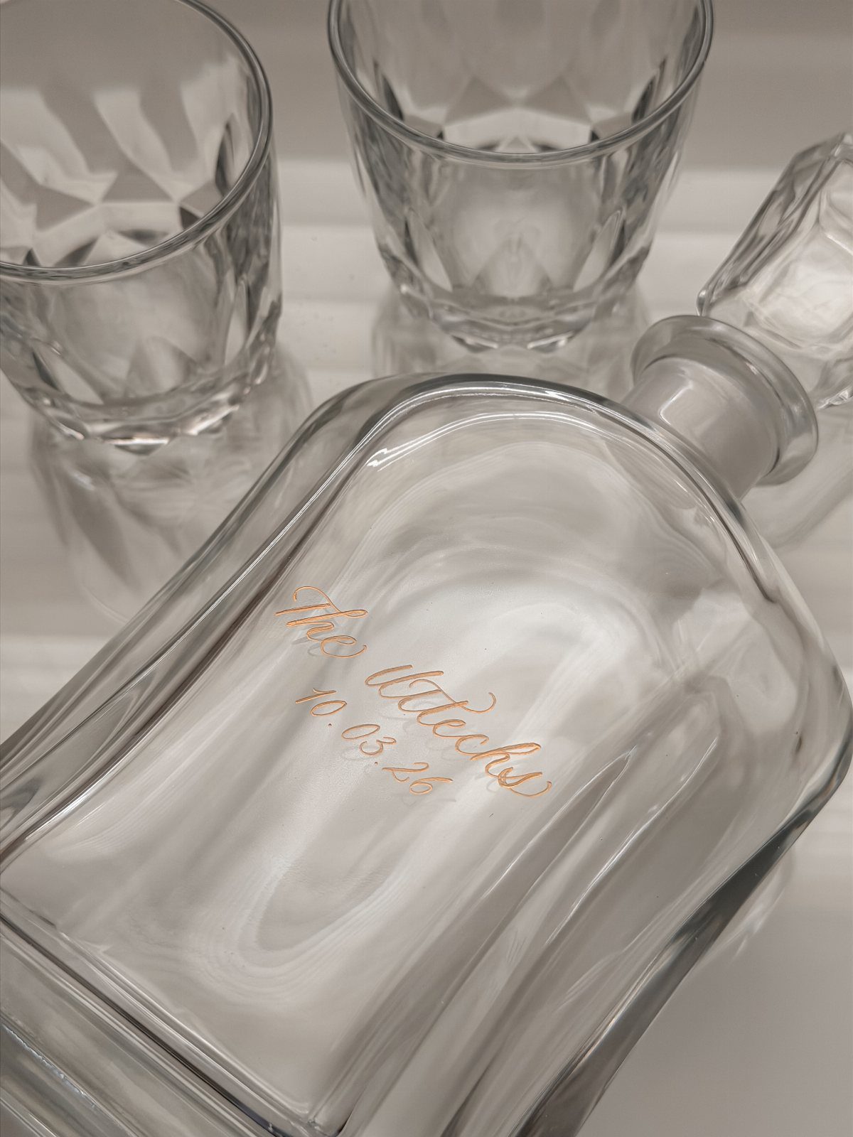 Engraved glass decanter and two crystal glasses on a white background