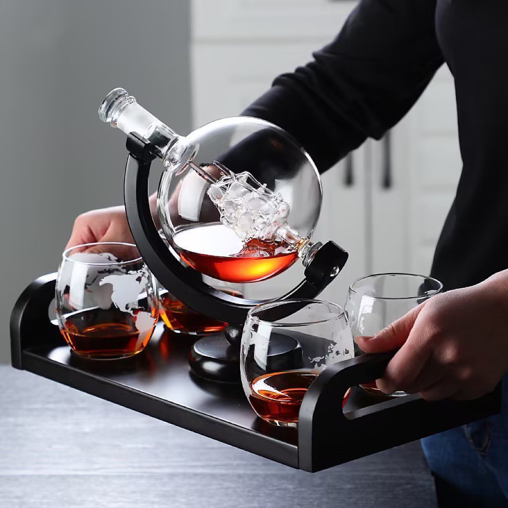 Globe-shaped whiskey decanter set with matching glasses on a black serving tray.
