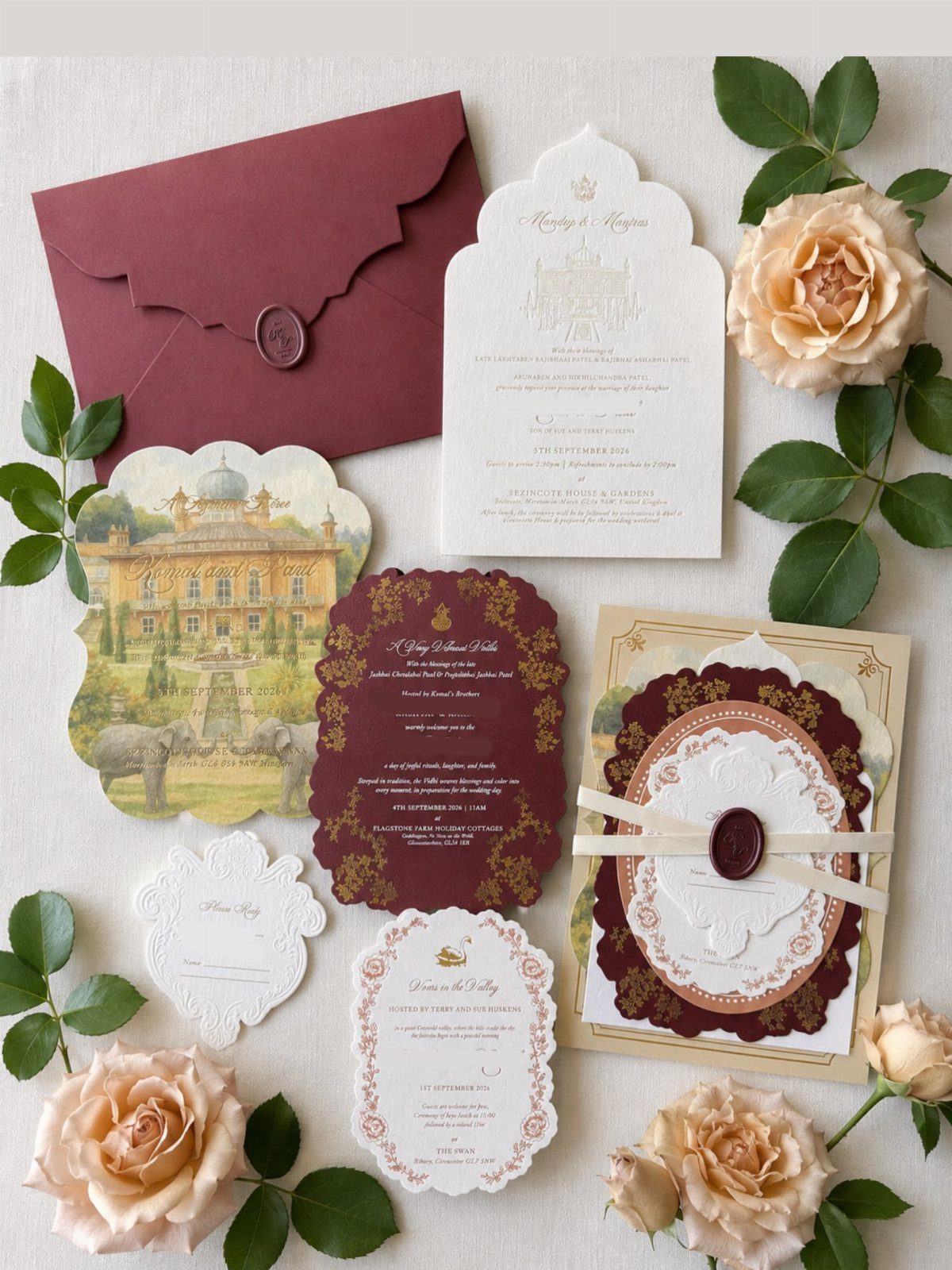 Wedding invitation suite with burgundy and white cards, wax seals, and peach roses.
