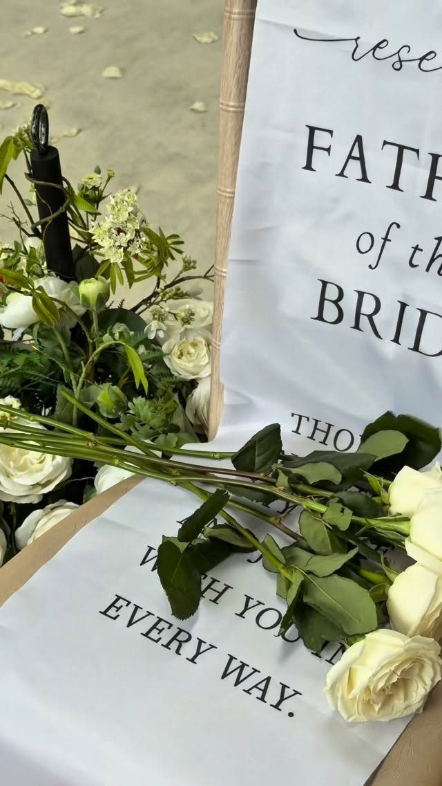 White reserved sign for father of the bride decorated with white roses and greenery.