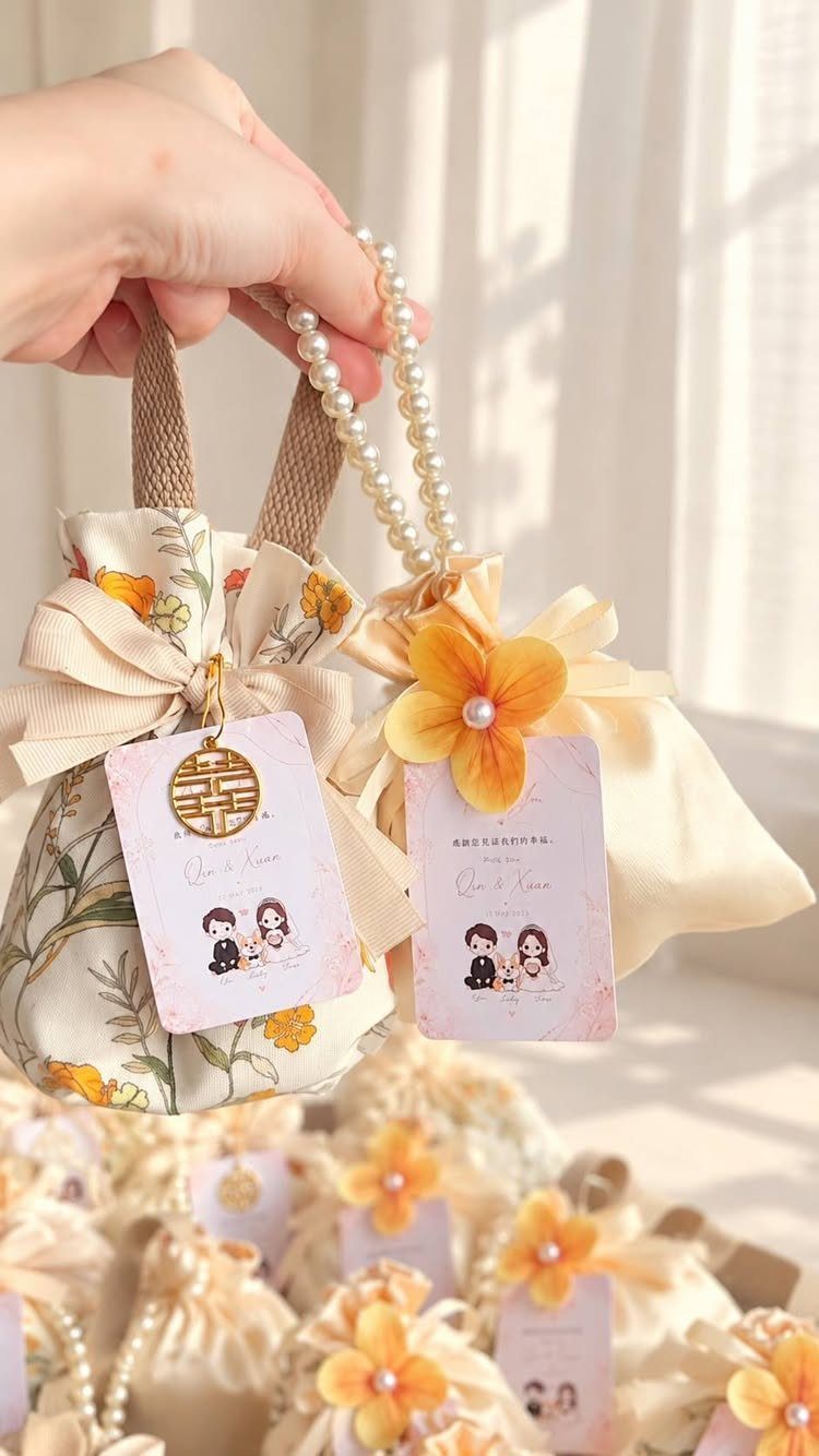 Small fabric drawstring favor bags with floral patterns and personalized couple tags.