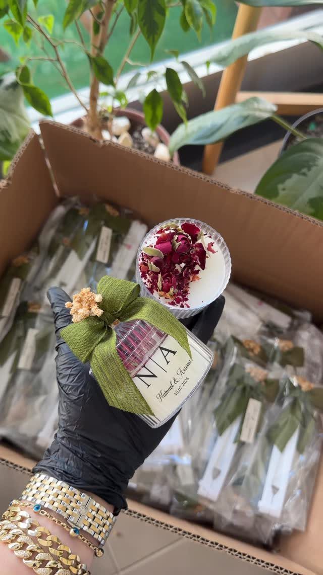 Small white candle with dried rose petals and green ribbon in a box