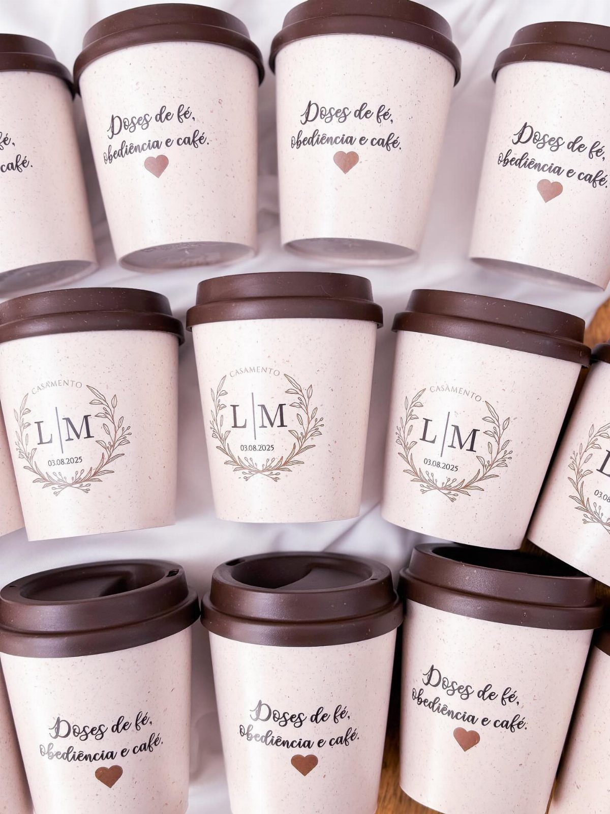 Small pink coffee cups with personalized logos and text as wedding favours.