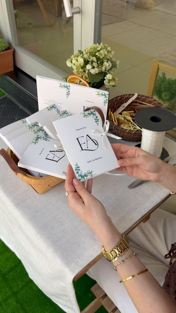 Hands holding a personalized white note card with green leaf accents and calligraphy.