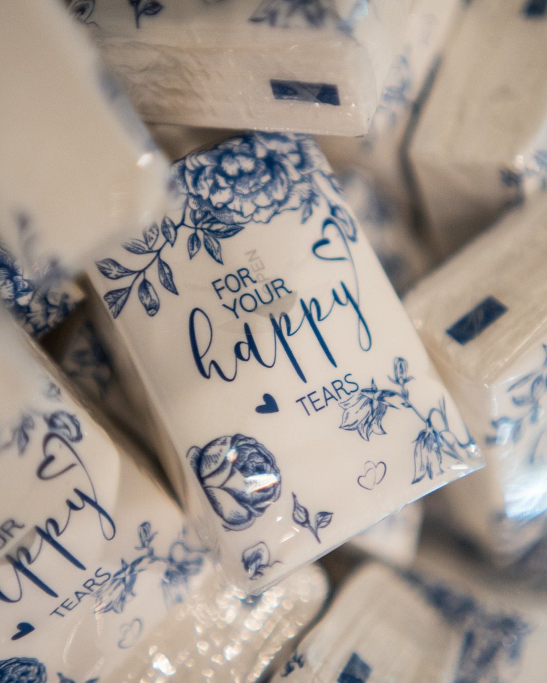 Small white tissue packets with blue floral designs and happy tears text.