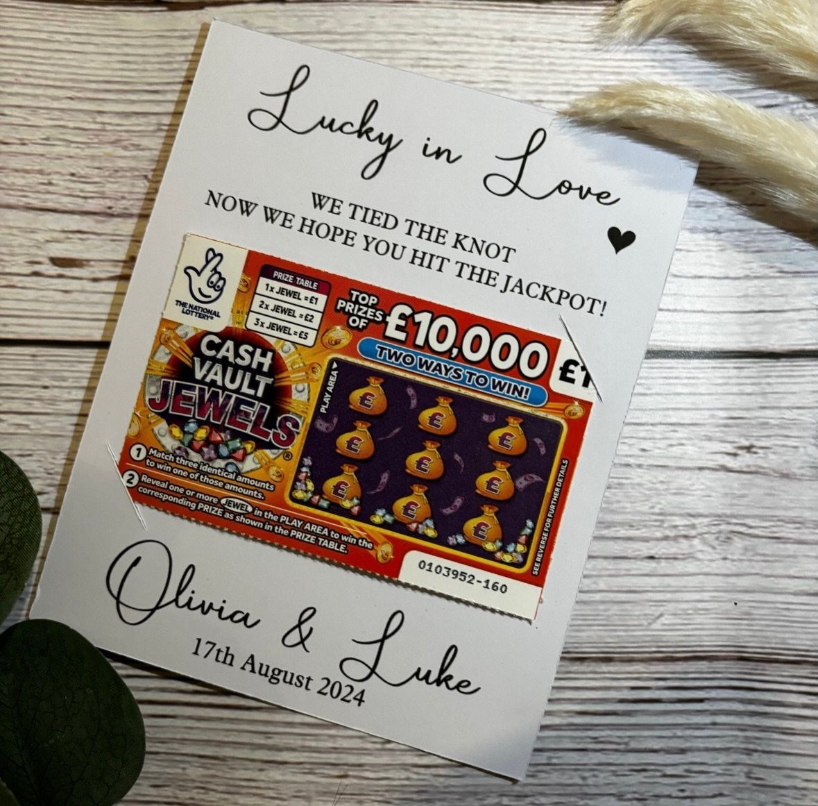 Scratch-off lottery ticket on a personalized wedding favor card on a wooden surface.