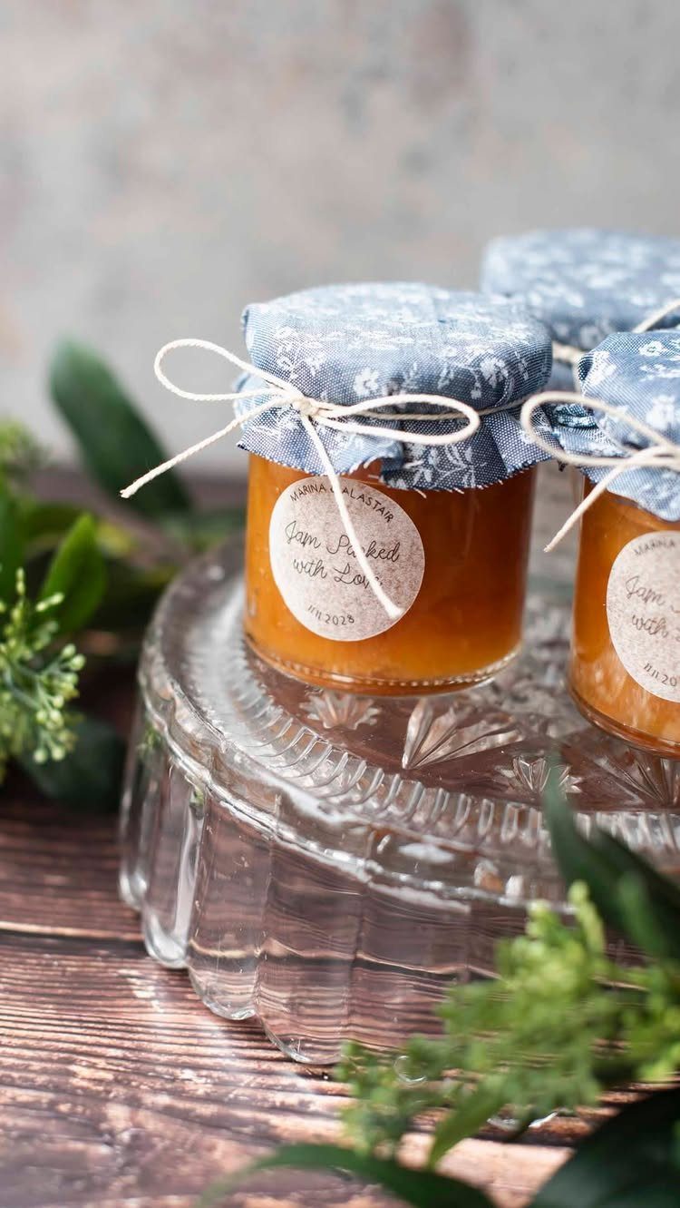 Mini jam jars with fabric lids and twine on a glass pedestal.