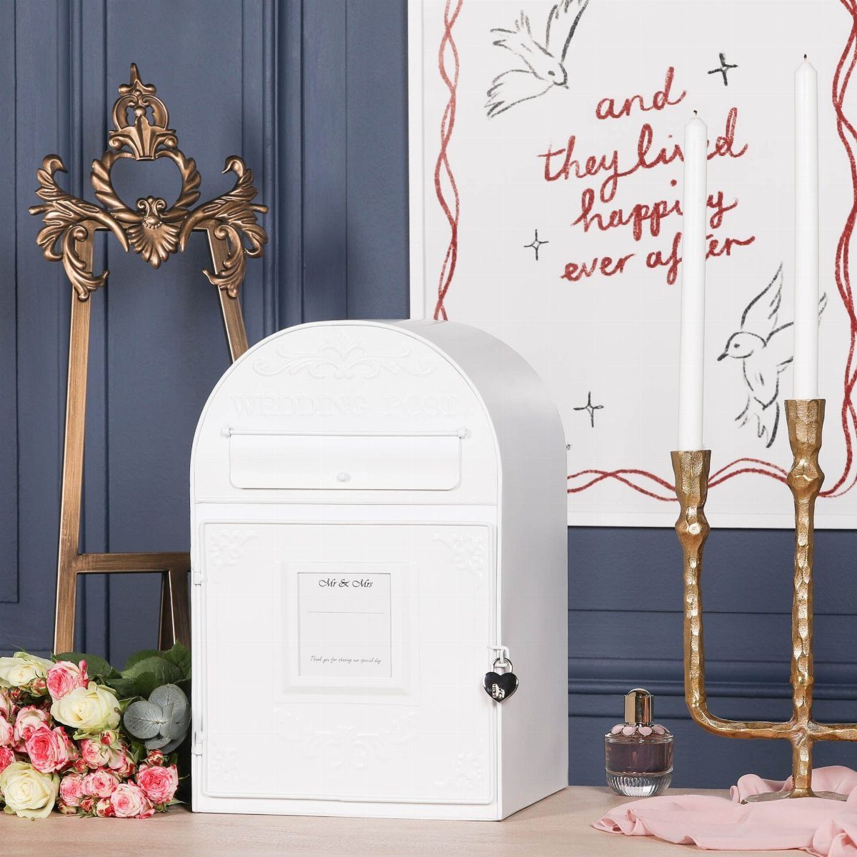 White metal wedding card mailbox with a lock and floral decorations nearby.