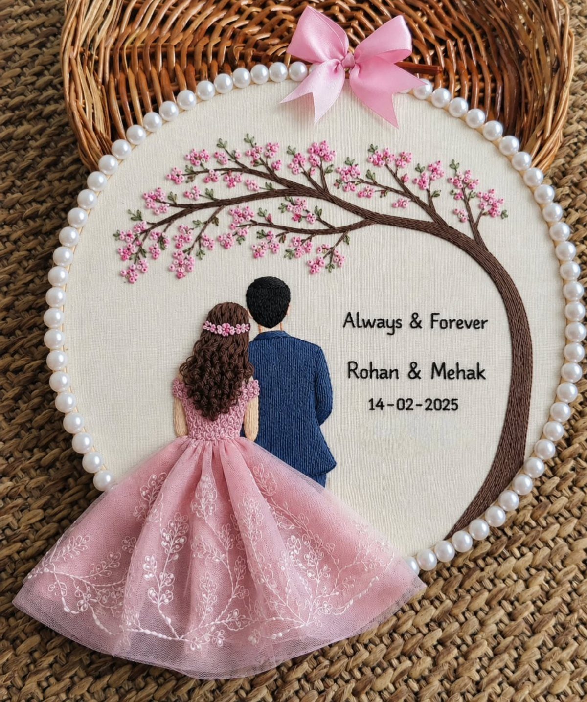 Embroidered wedding hoop with 3D couple under a pink flowering tree and names.