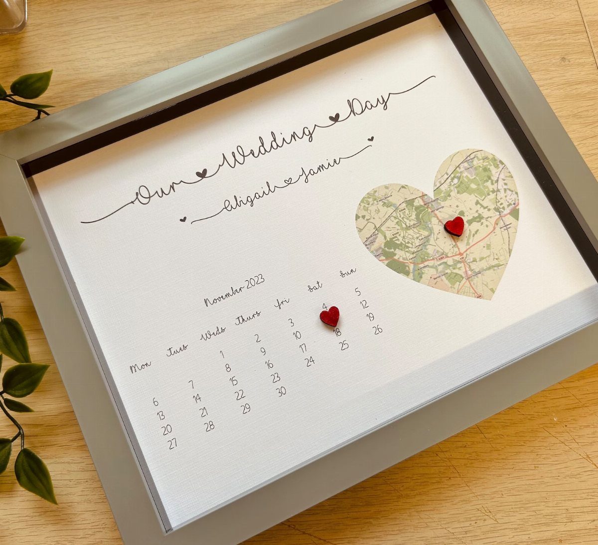 Framed wedding art featuring a heart-shaped map and a marked November calendar.