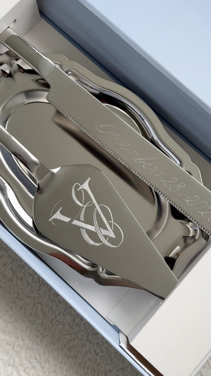 Engraved silver cake server and knife set inside a white gift box.