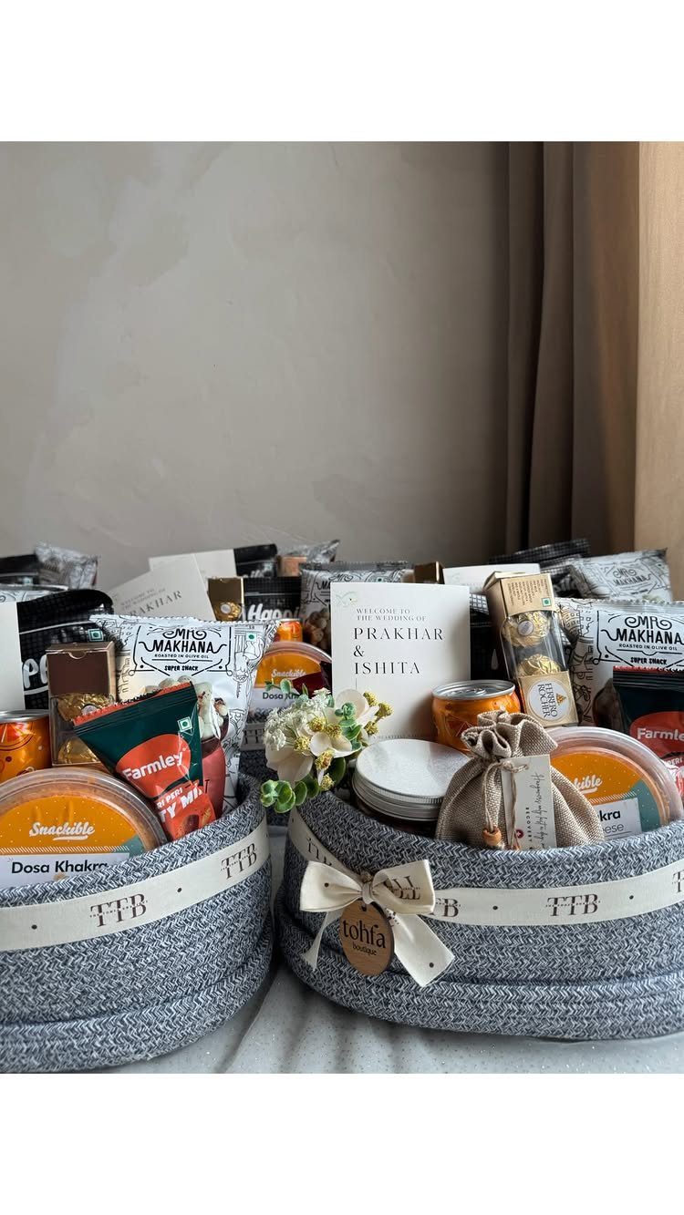 Two grey fabric gift baskets filled with assorted gourmet snacks and food items.