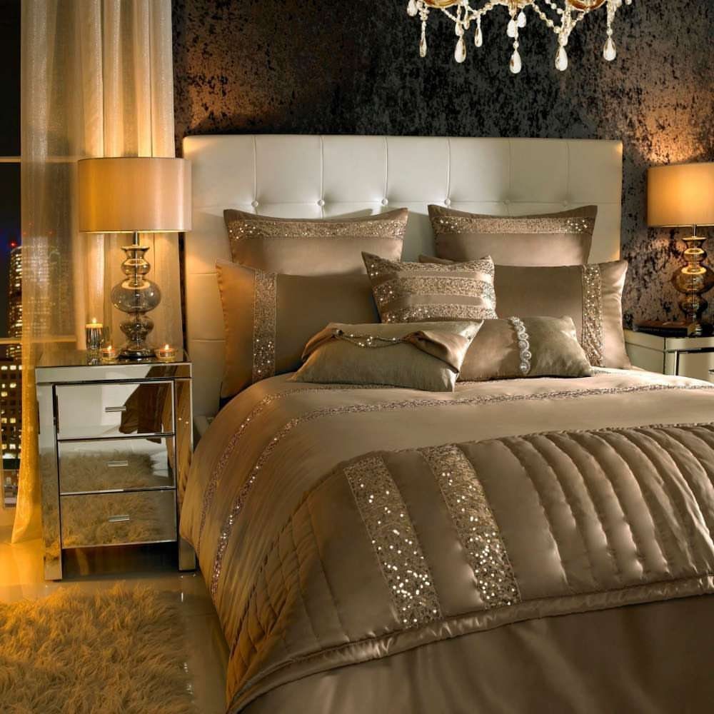 Champagne satin bedding set with sequin details on a bed with tufted headboard.