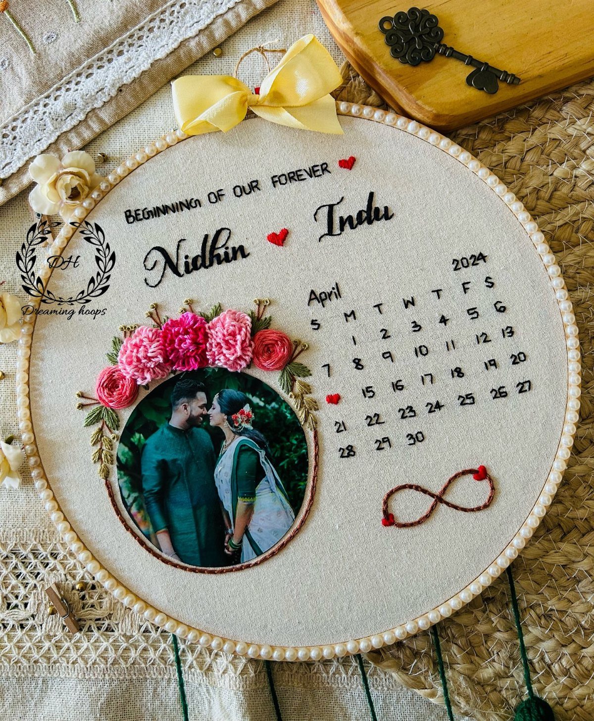 Embroidered hoop art with a couple's photo, floral accents, and a personalized calendar.