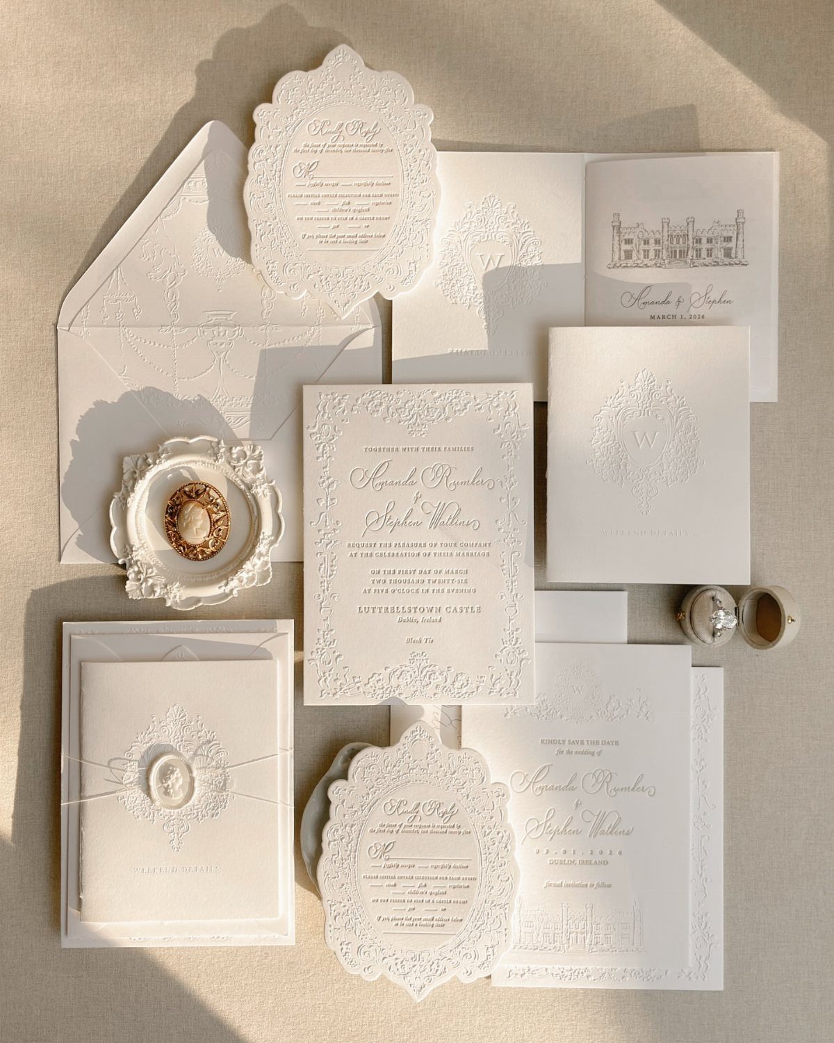 White embossed wedding invitations with elegant script and floral patterns on beige background
