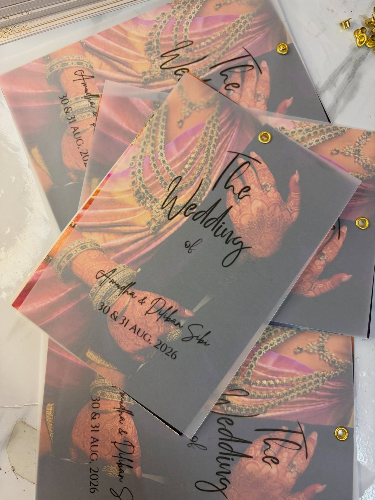 Translucent acrylic wedding invitations with traditional Indian bridal imagery and gold rivets.