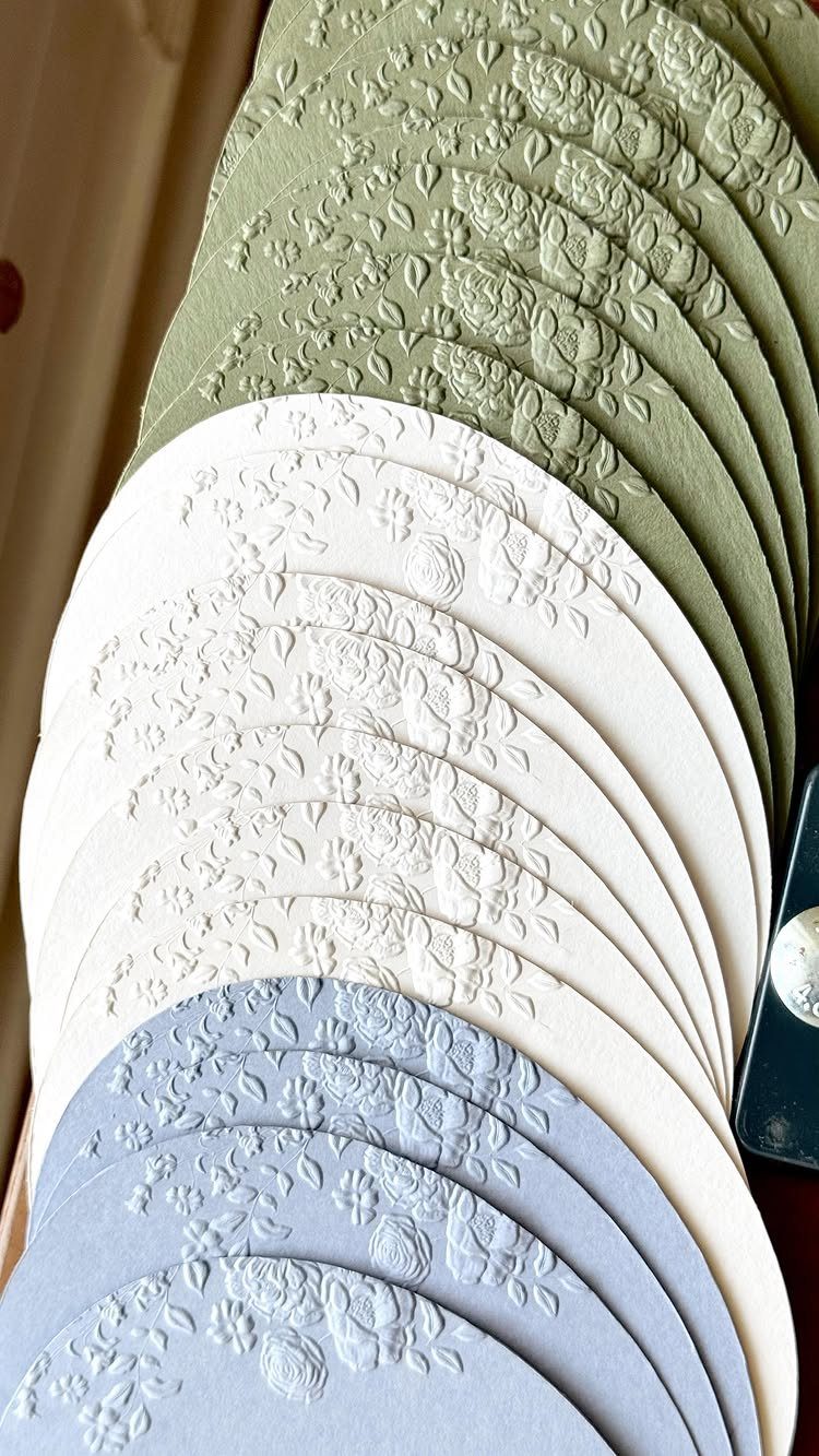 Arched cardstock papers in green, white, and blue with embossed floral patterns.