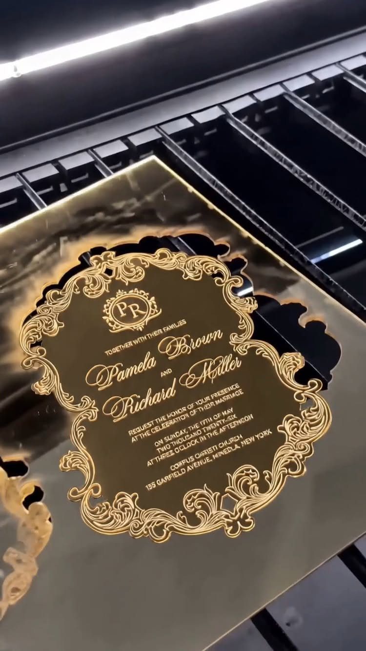Gold acrylic wedding invitation with ornate borders and elegant cursive calligraphy text.