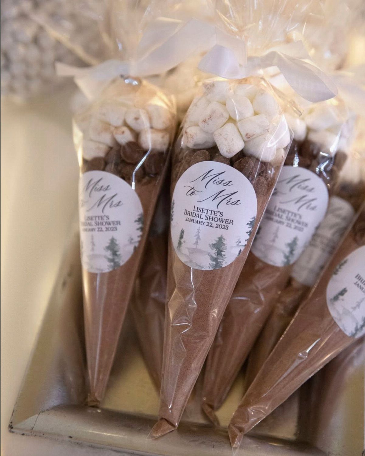 Hot chocolate kits in cone bags with marshmallows and bridal shower labels.