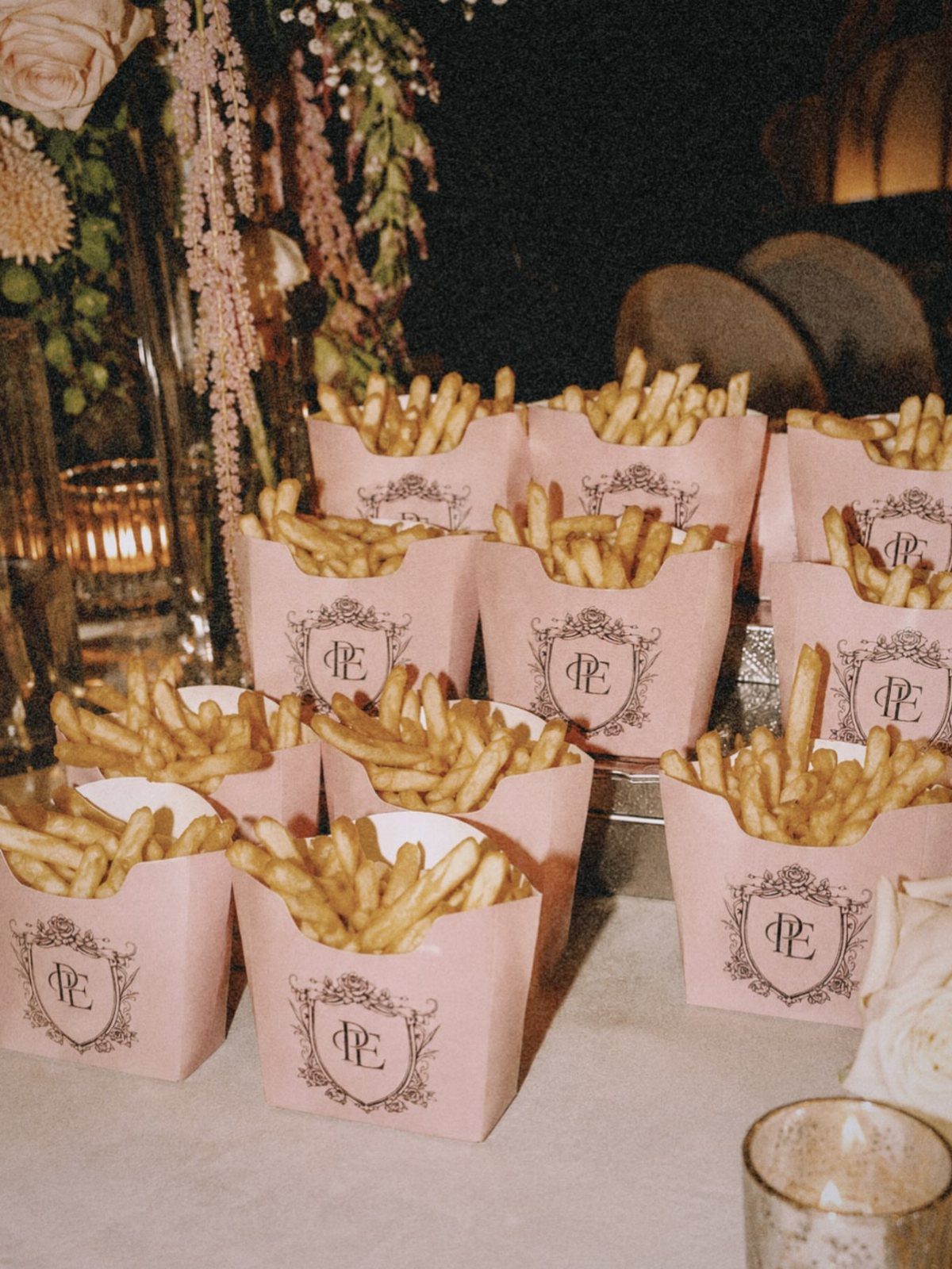Pink cardboard containers filled with french fries featuring a personalized monogram crest.
