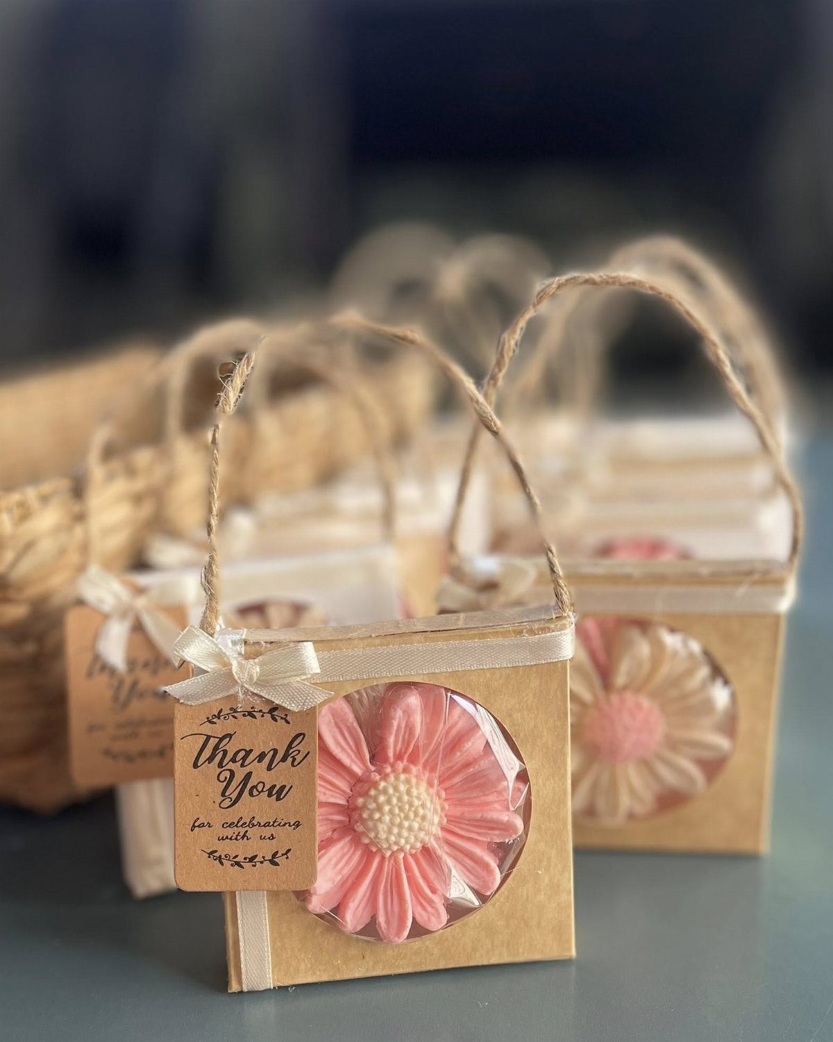 Pink flower-shaped soaps in small brown cardboard boxes with thank you tags.