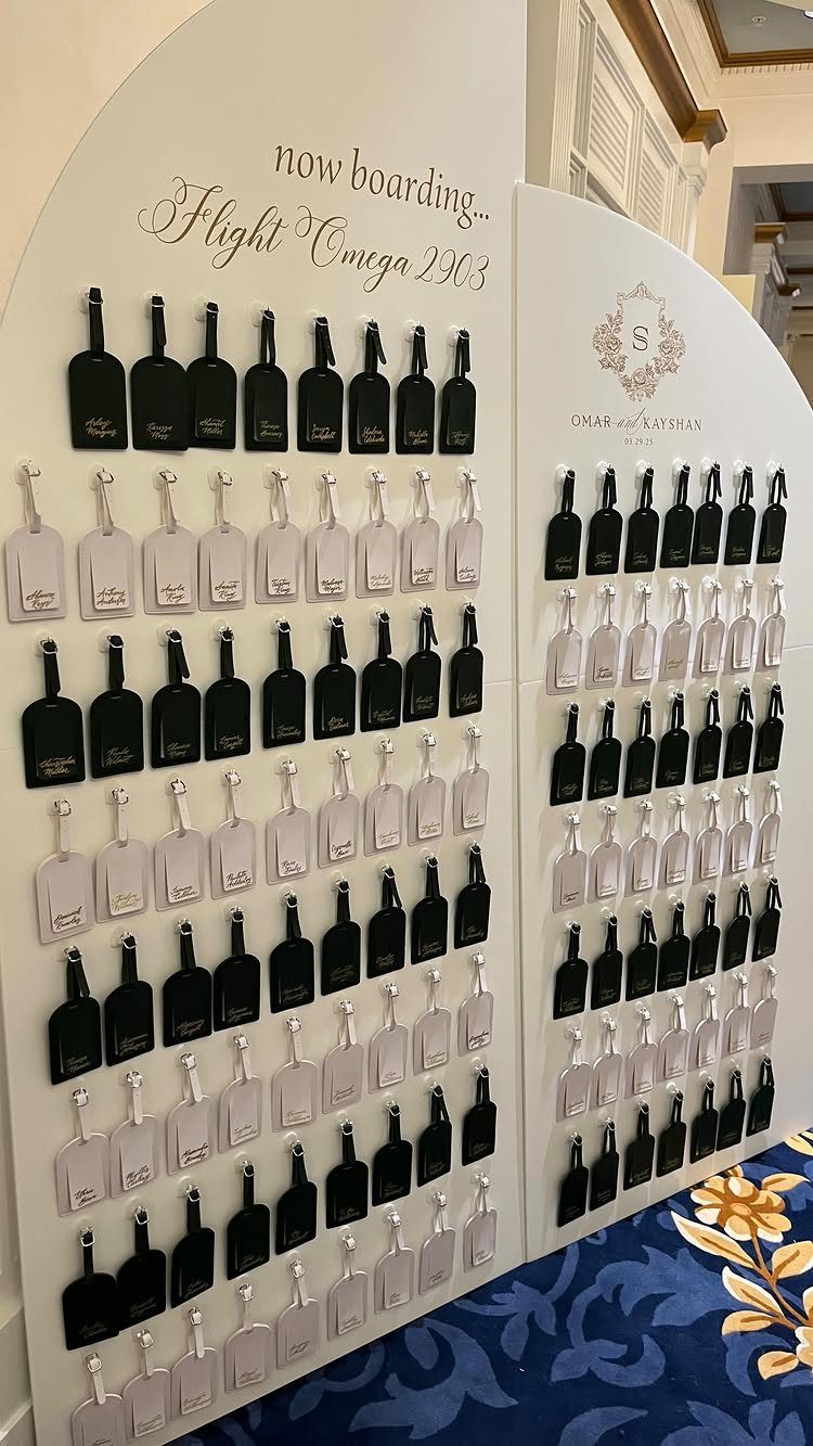 Black and white luggage tags displayed on a white wall for a wedding.