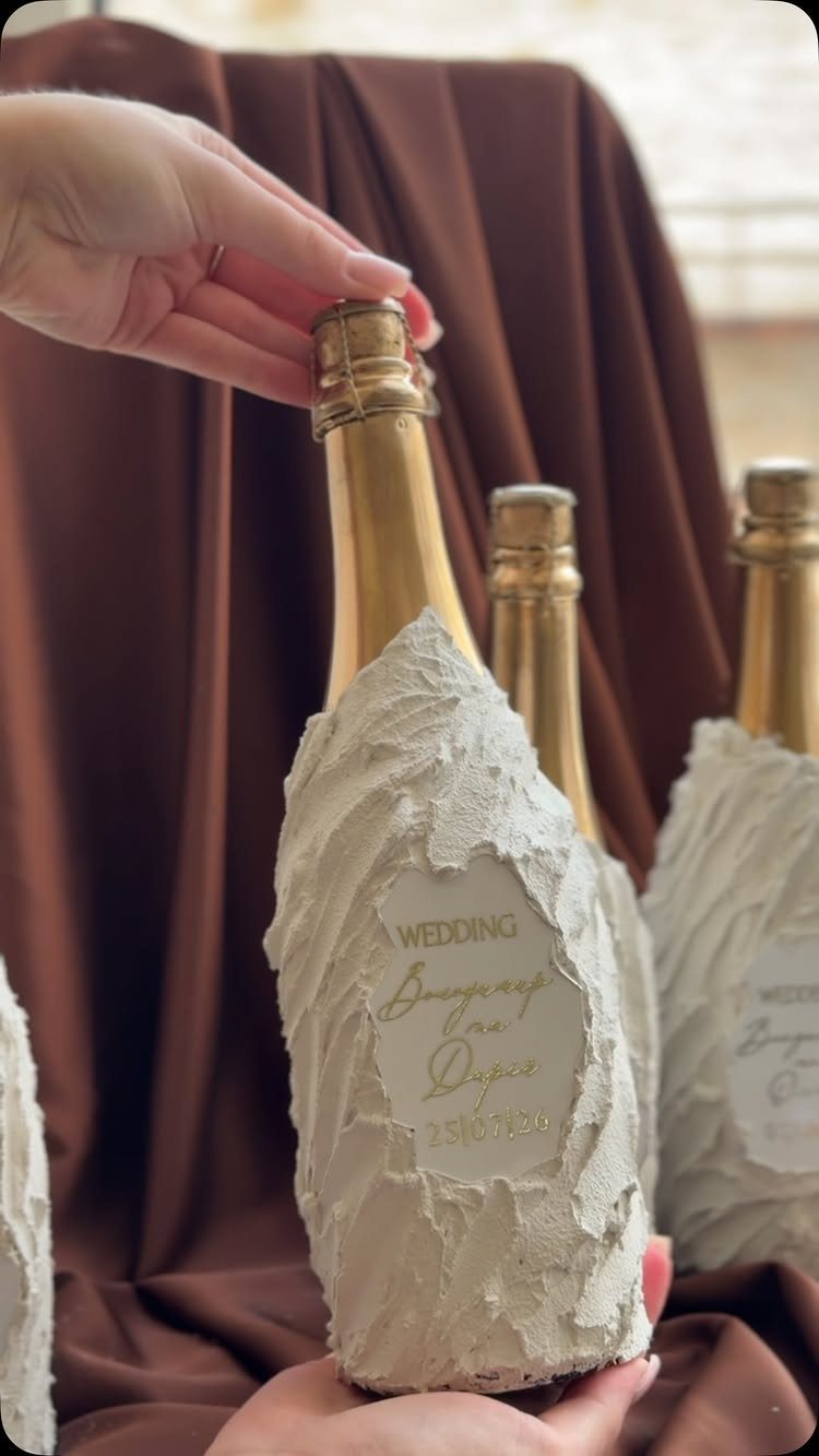 Mini champagne bottle encased in textured white plaster with a wedding label