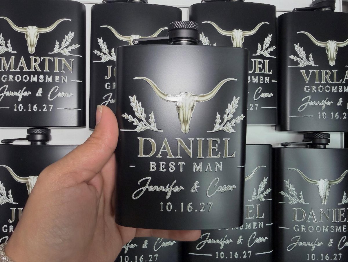 Matte black mini flasks engraved with longhorn skulls and personalized wedding party names.