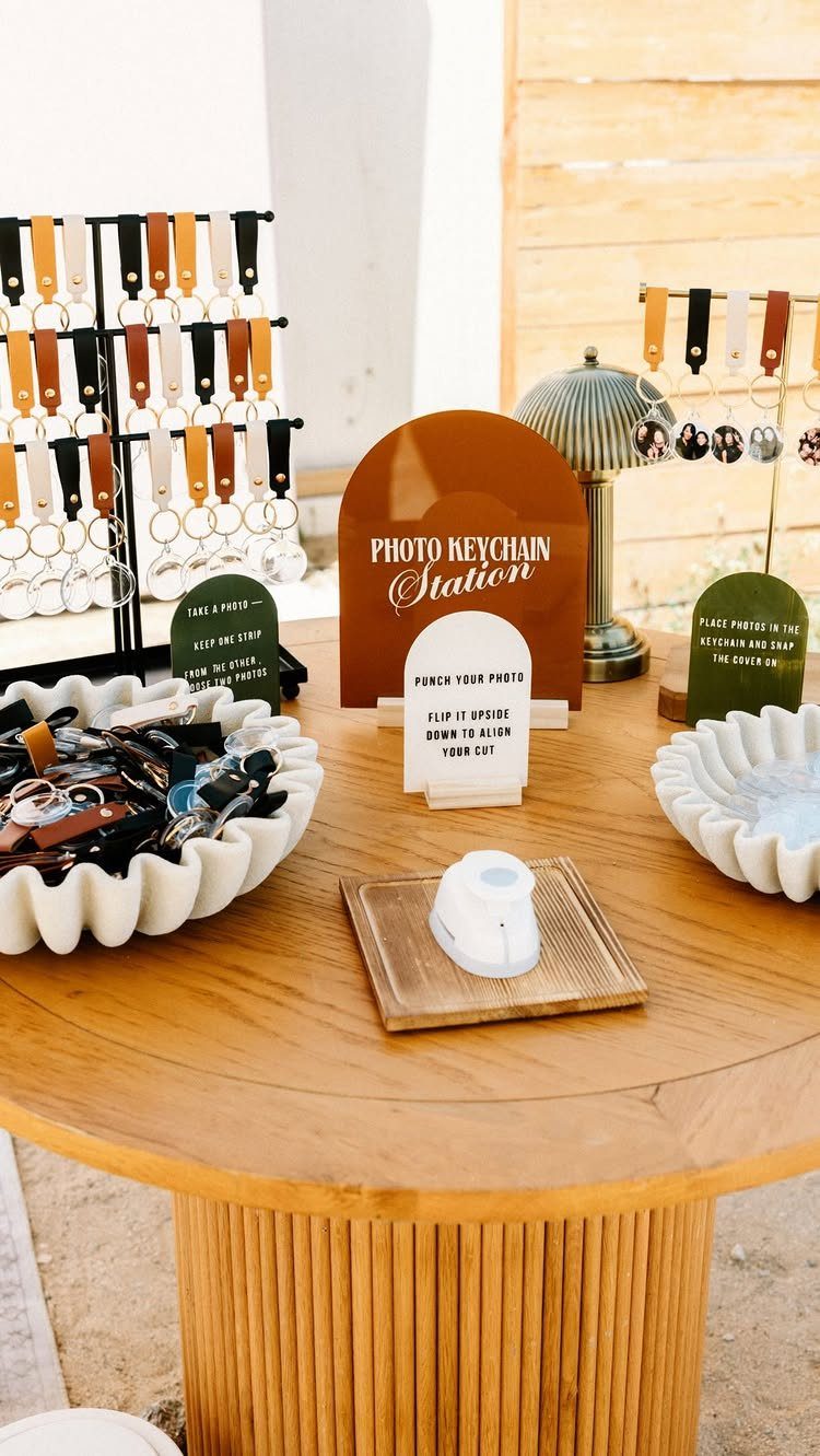 Photo keychain station on a wooden table with leather straps and punch machine.