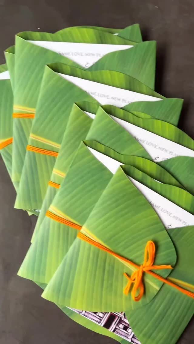 Green leaf-textured envelopes tied with orange string containing white invitation cards.