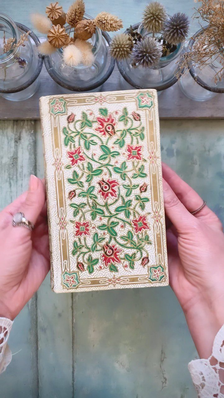 Vintage book with red and green floral cover held by two hands