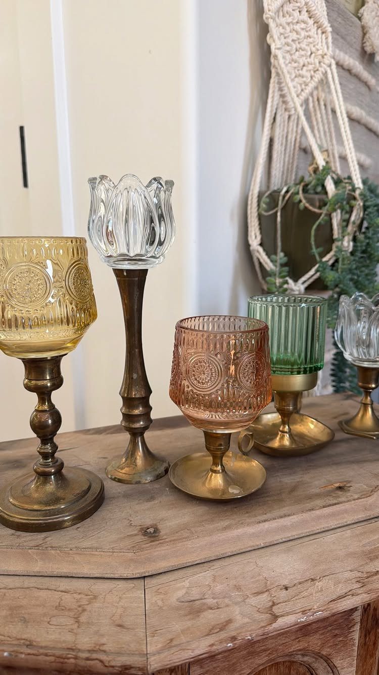 Vintage colored glass goblets with brass stems on a rustic wooden table.