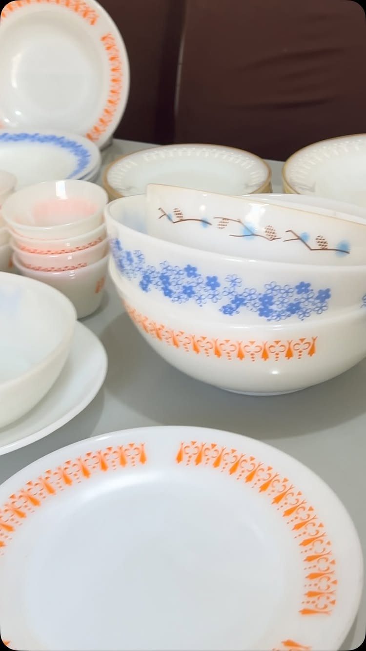 Vintage white milk glass dinnerware set with orange and blue floral rim patterns.