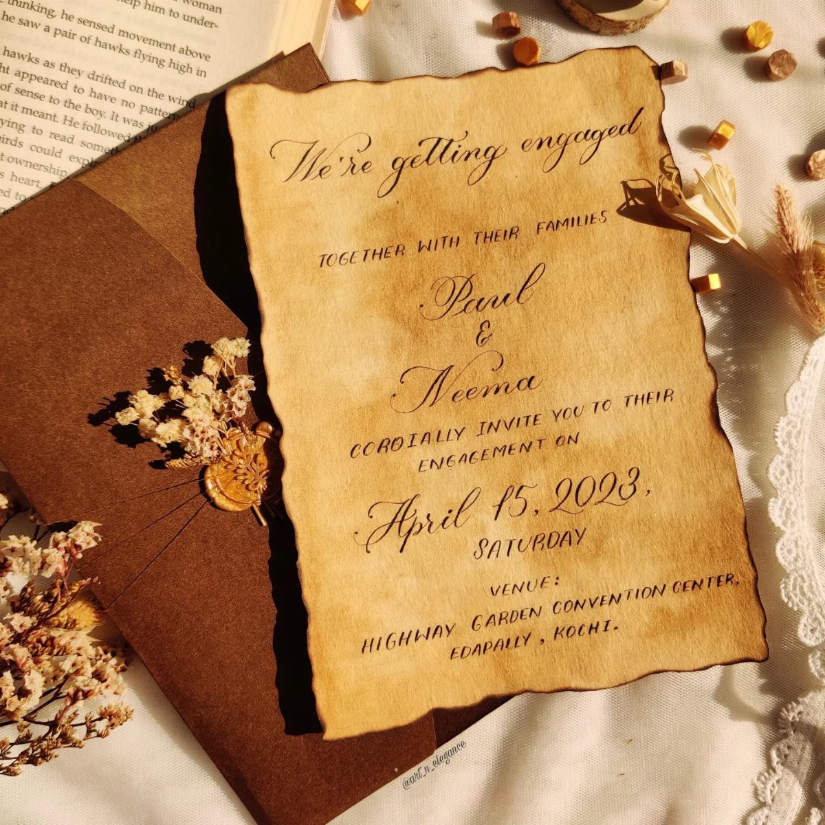 Parchment engagement invitation with burnt edges and wax seal on lace fabric