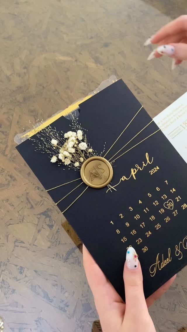 Handmade navy blue wedding card with gold calendar, wax seal, and dried flowers.