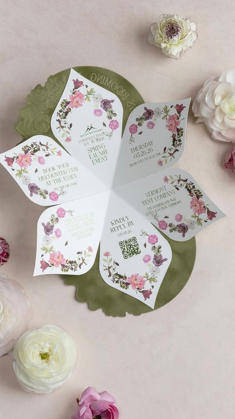 Flower-shaped wedding invitation with floral designs on a green base and white flowers.
