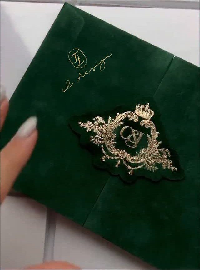 Green velvet envelope with a gold foiled crest and ornate floral details.