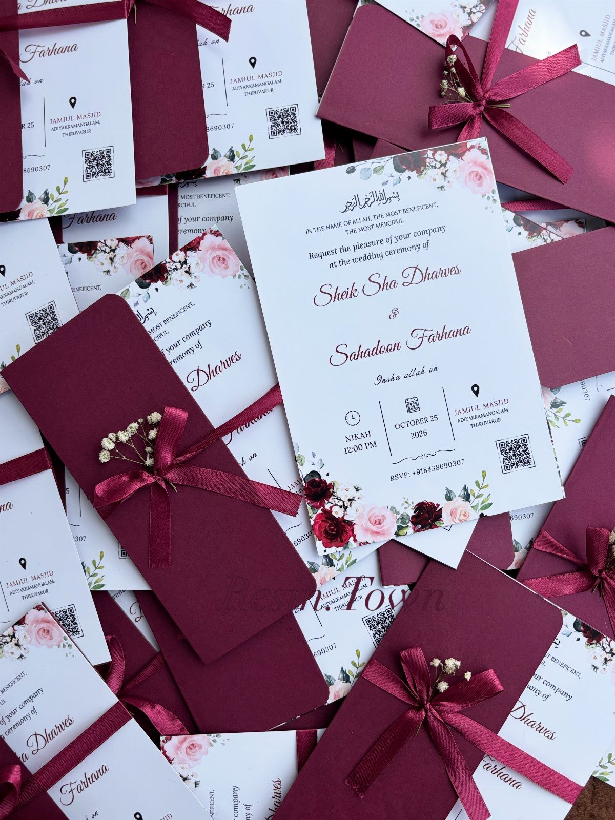 Wedding invitations with burgundy envelopes, satin ribbons, and floral designs on white cards.