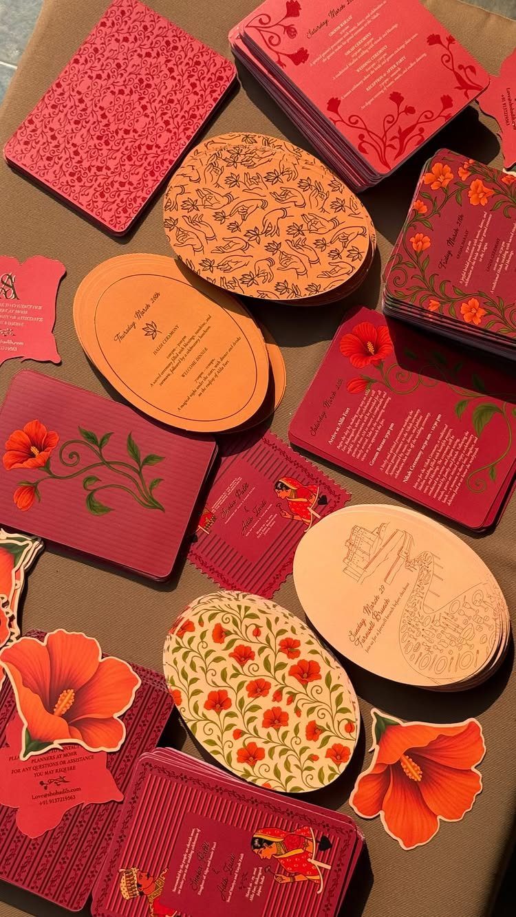Various pink and orange wedding invitation cards with floral designs and different shapes.