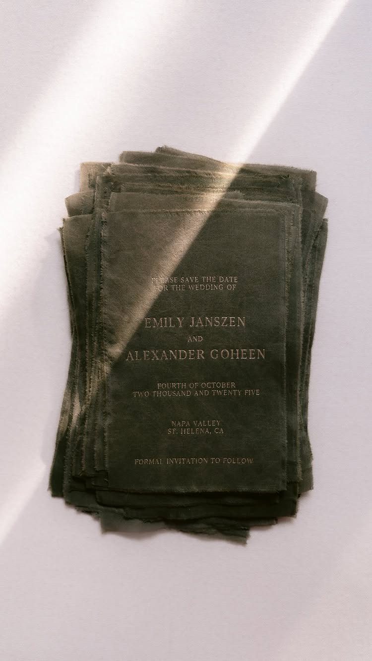 Dark grey textured wedding invitations with white text stacked on a white background.