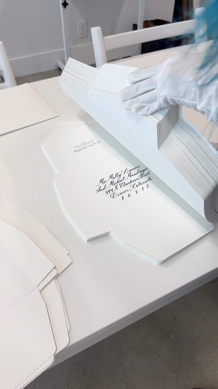 White envelopes with elegant black cursive printed addresses on a white table.