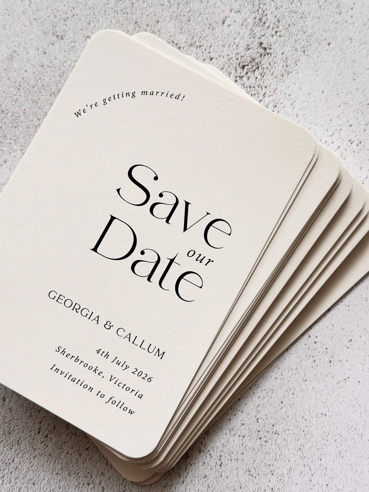 Stack of cream save the date cards with black serif typography on textured background