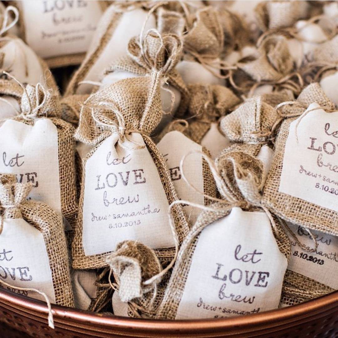 Burlap favor bags with tags reading let love brew in a copper bowl