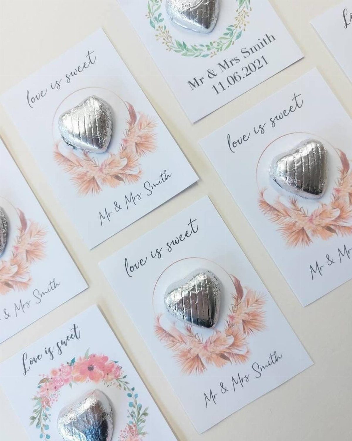 Wedding favor cards with silver heart chocolates and the phrase love is sweet.