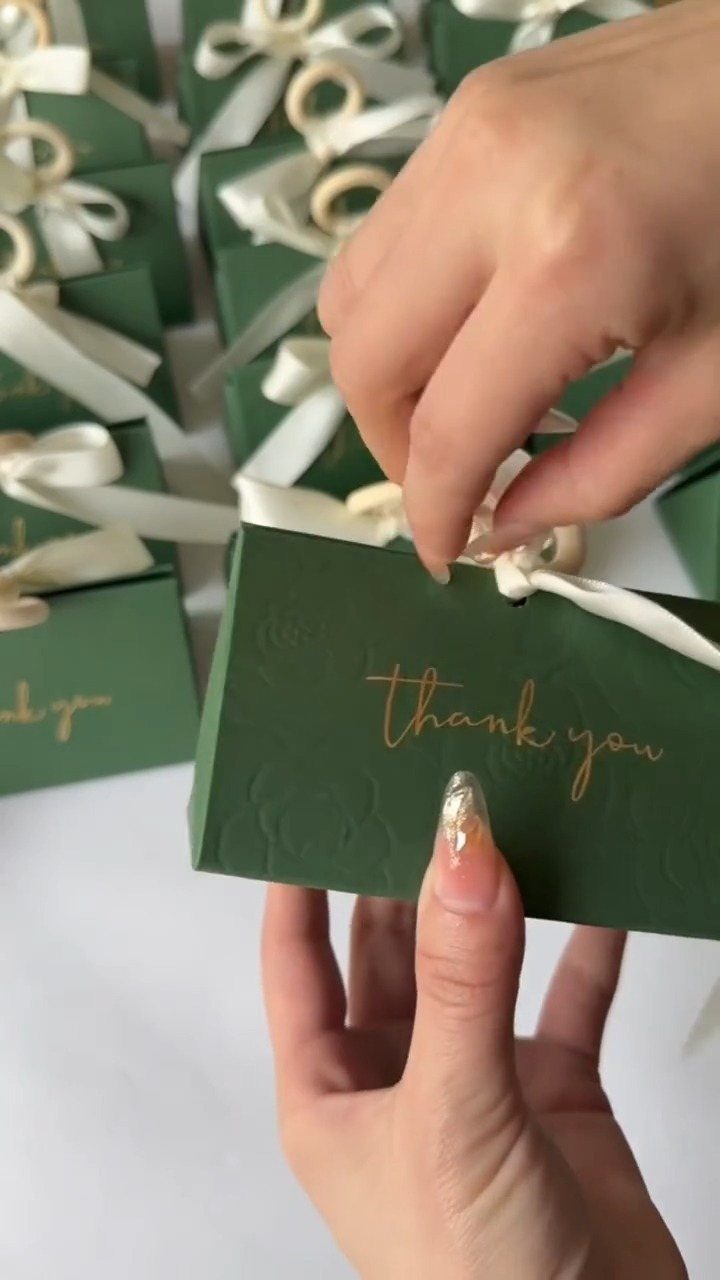 Green gift boxes with gold thank you text and white ribbons for wedding favors