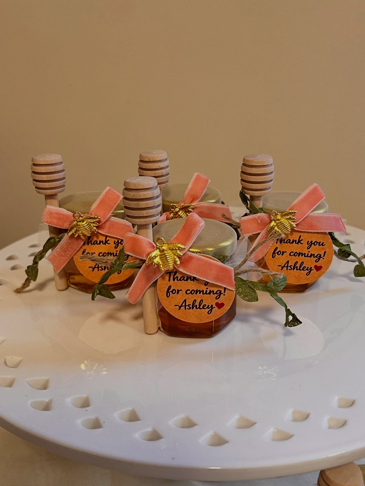 Honey jar wedding favors with pink ribbons and thank you labels on white stand