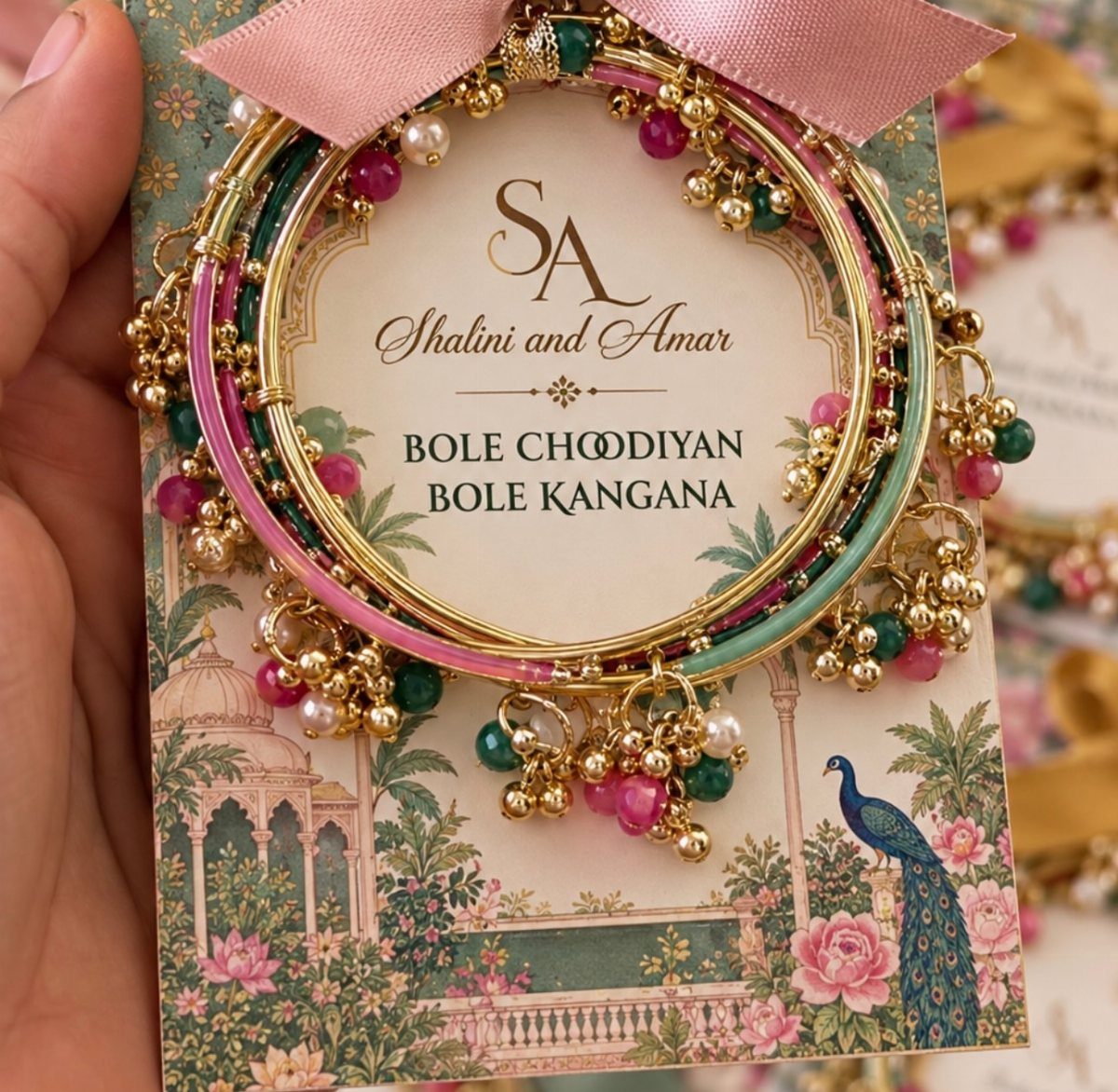 Ornate gold and colorful Indian bangles with pearls on a decorative wedding card.