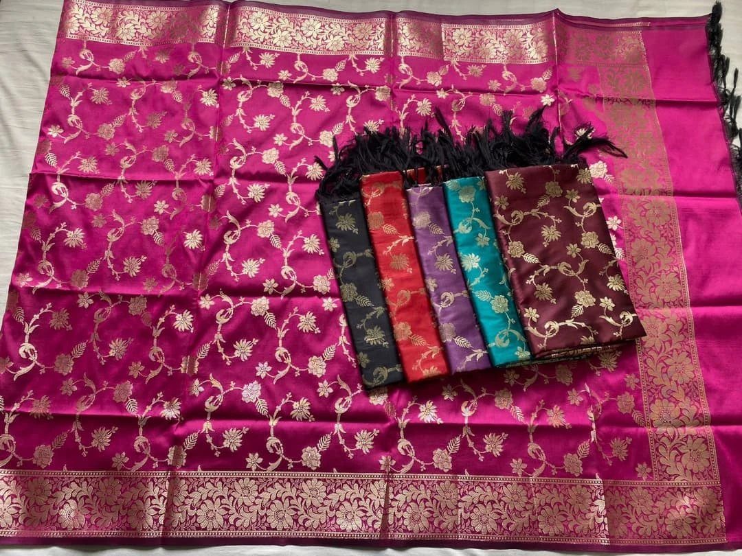 Pink silk dupatta with gold zari patterns and several folded colorful dupattas on top.