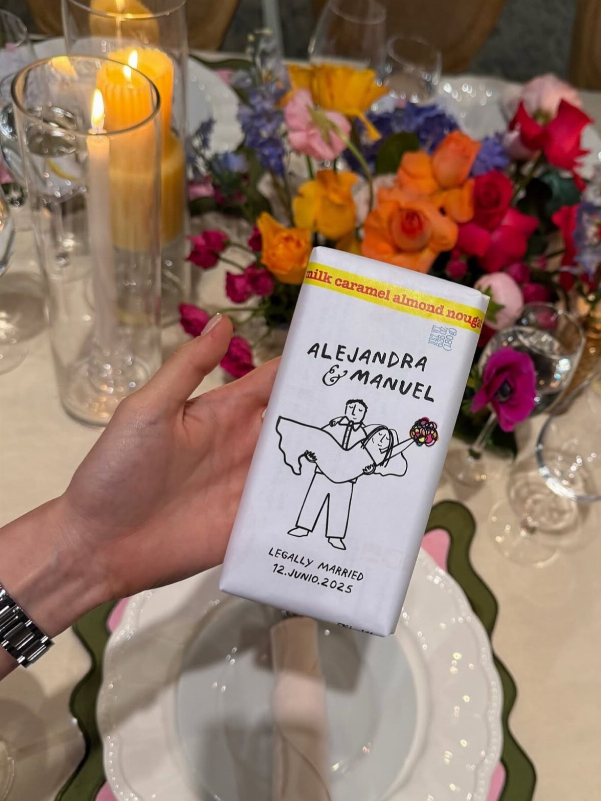 Customized chocolate bar wrapper with wedding illustration held over a decorated table.